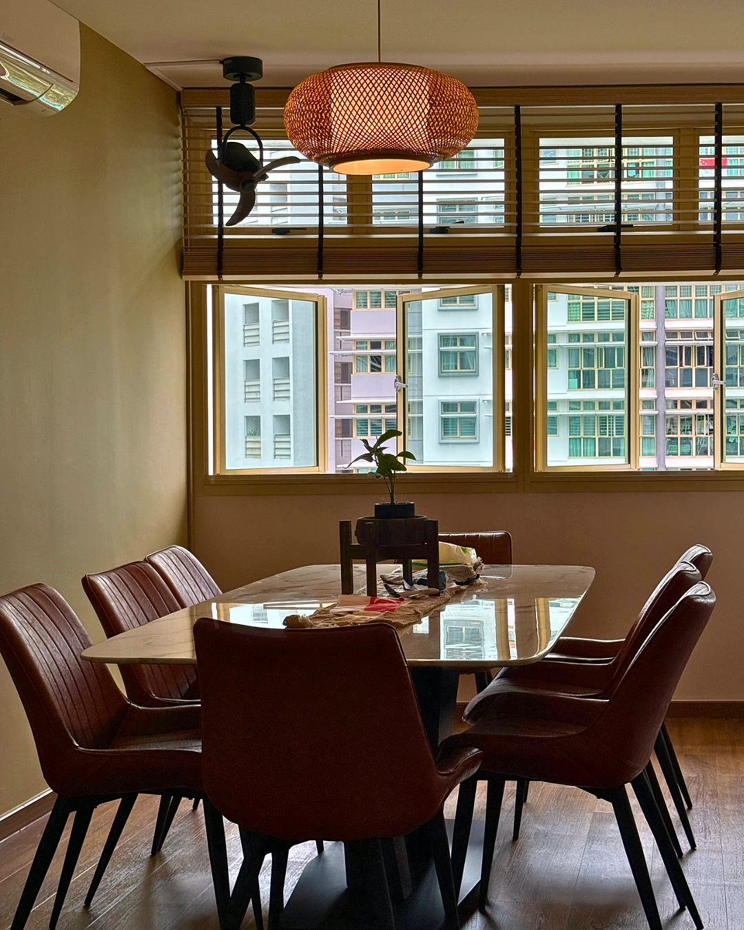 Dining table with a pendant lamp and city-facing windows.