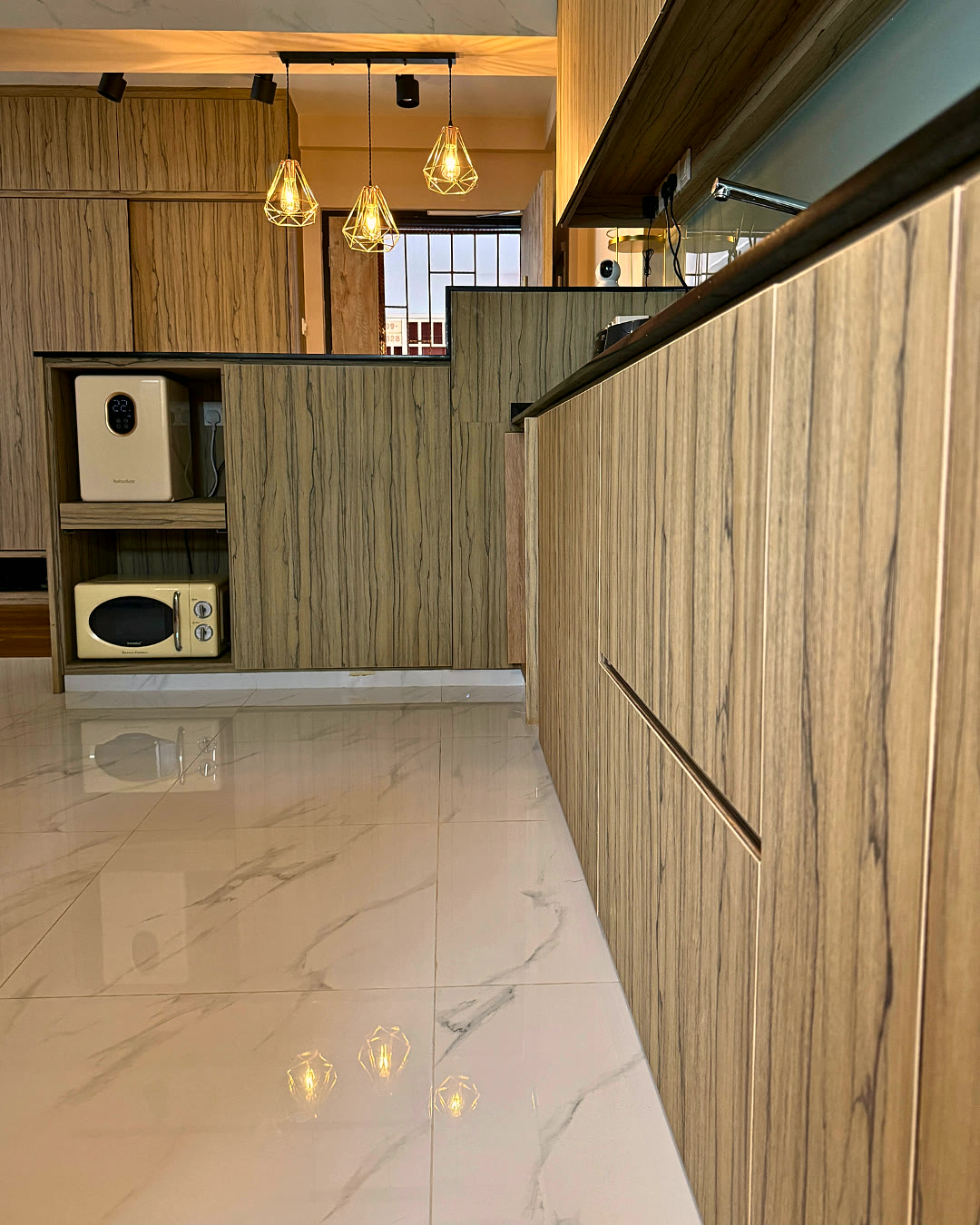 Kitchen counter with warm-oak cabinetry and pendant lighting.
