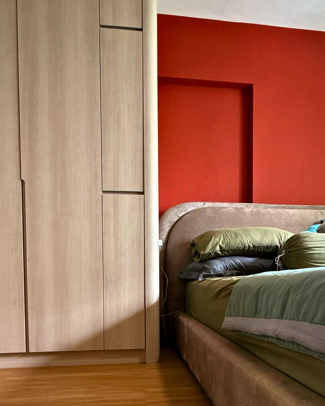 Bedroom with a red accent wall and fitted wardrobes.