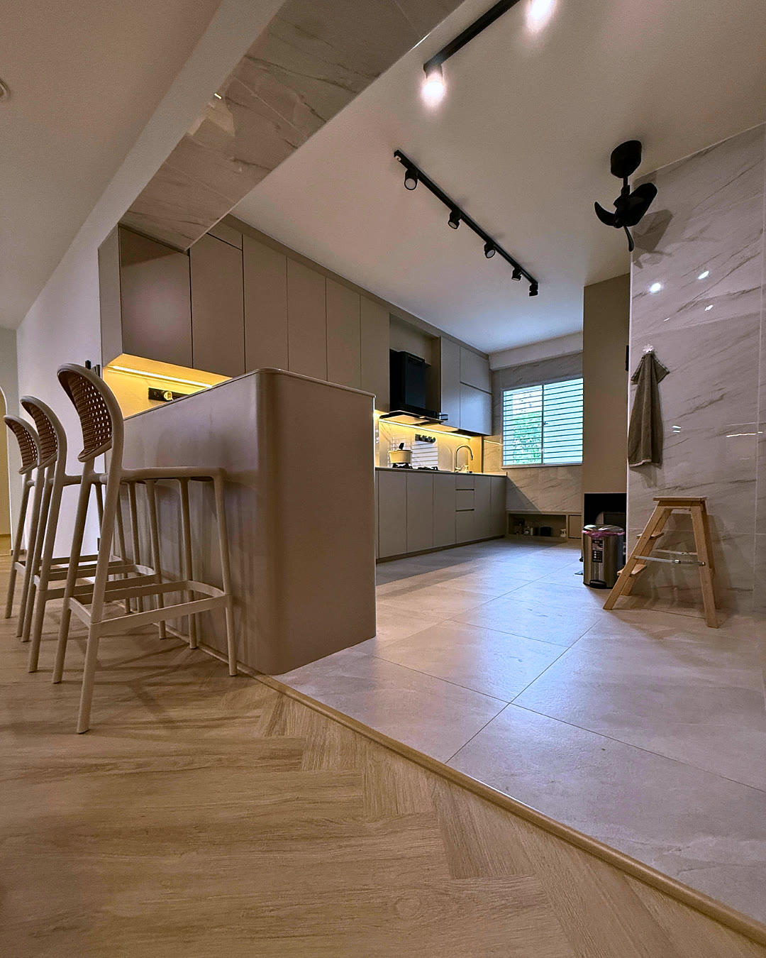 Kitchen island with rattan bar stools and herringbone flooring.