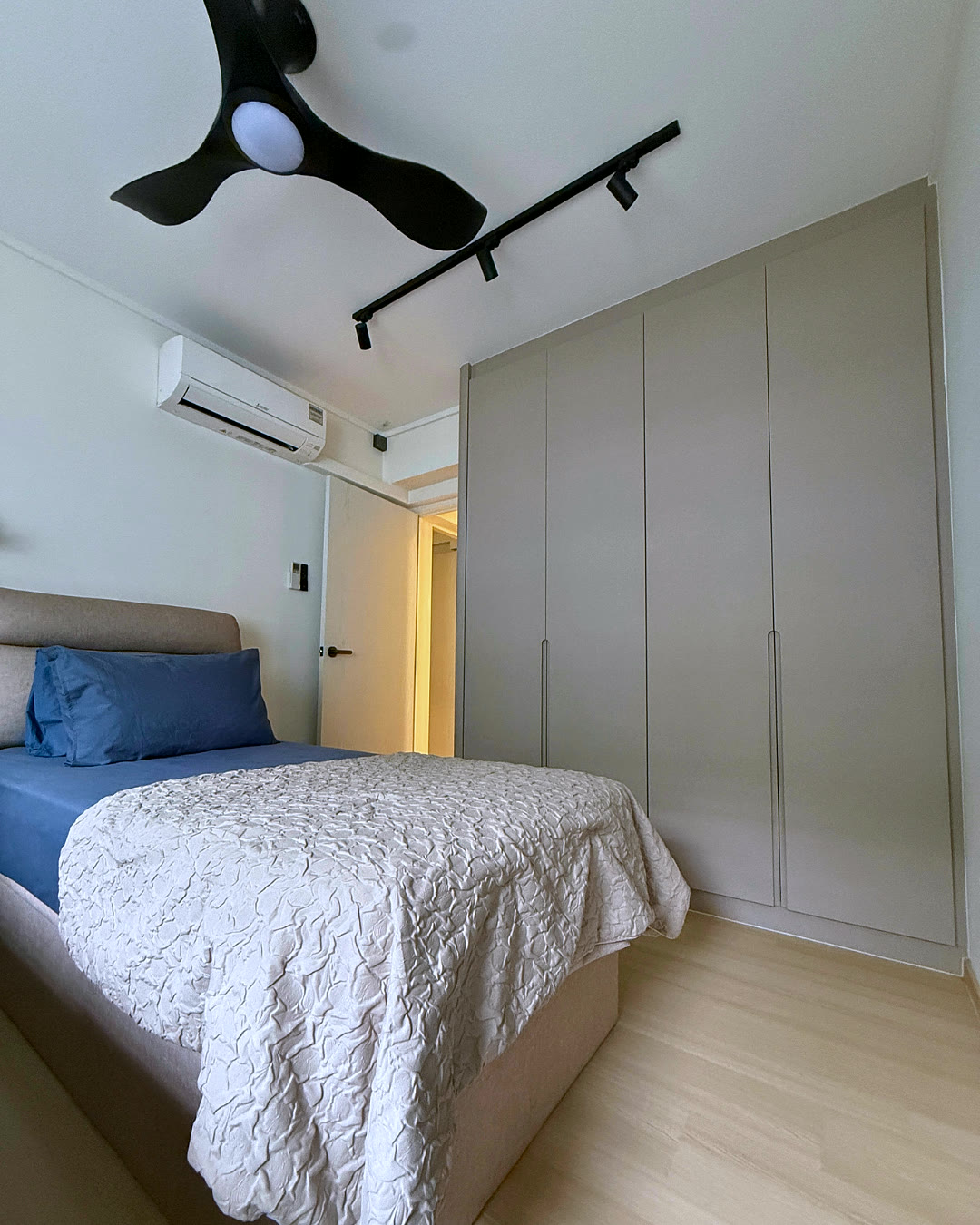 Bedroom with fitted wardrobes and a blue-linen bed.