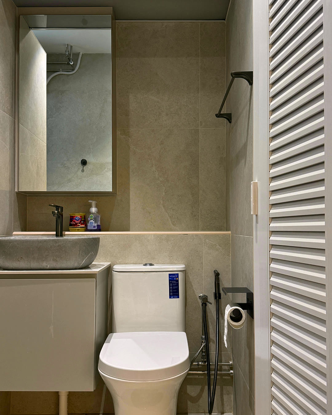 Bathroom with vanity mirror and louvred storage door.